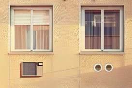 Gevel met links een klassieke airco-buitenunit en rechts twee kleine ronde muurdoorvoeren van een monoblock