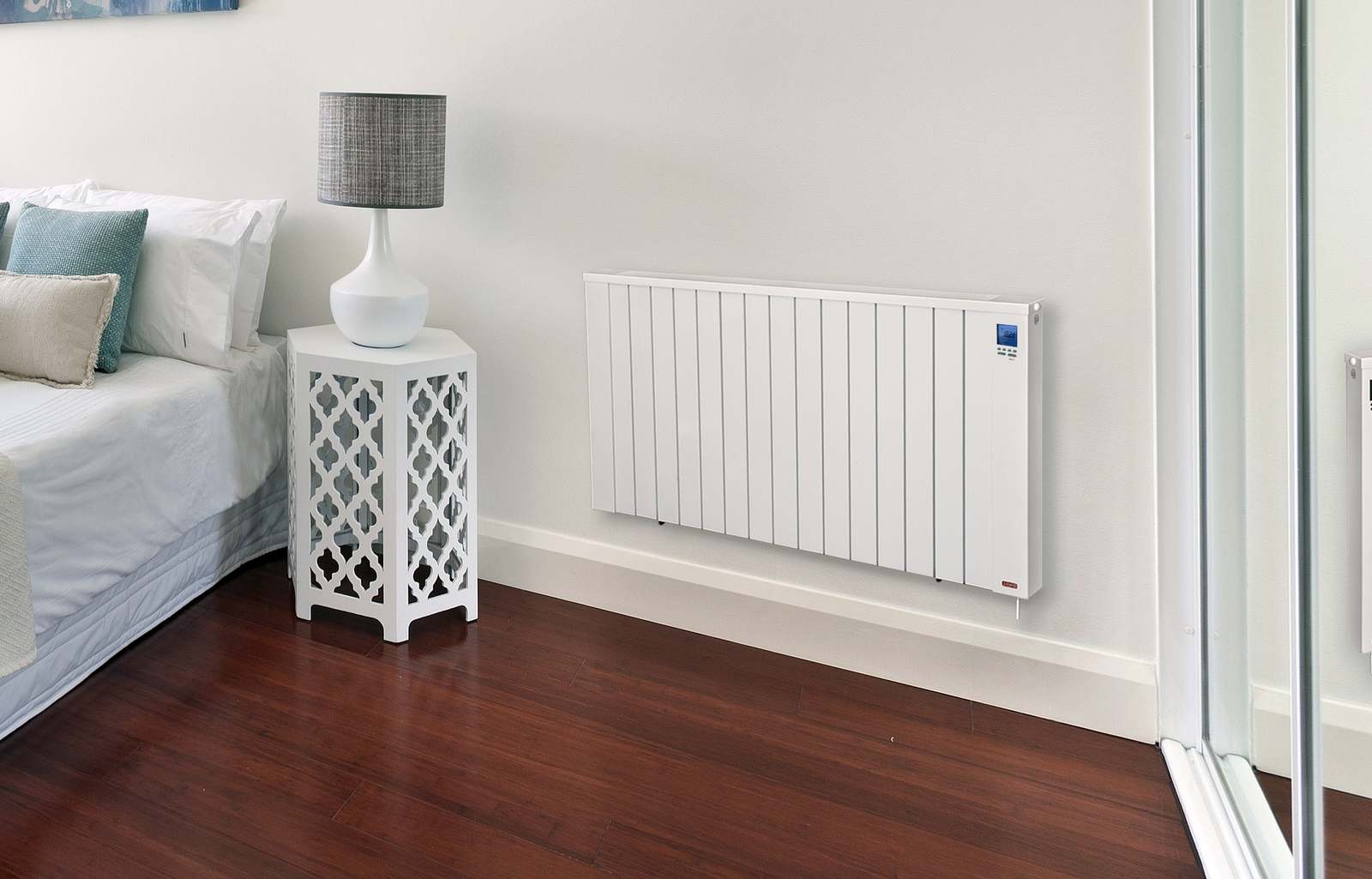 Slaapkamer met een platte witte Jawotherm Serie N radiator naast het bed